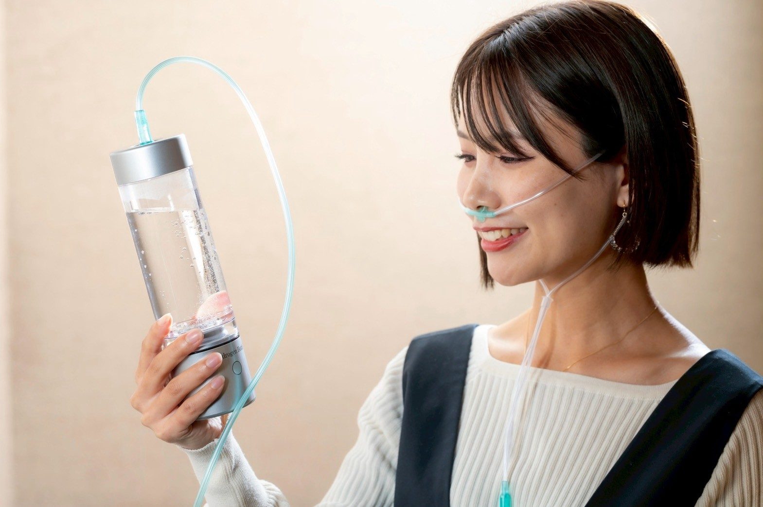 水素を吸いながら、ボトルを手に笑顔を見せる女性