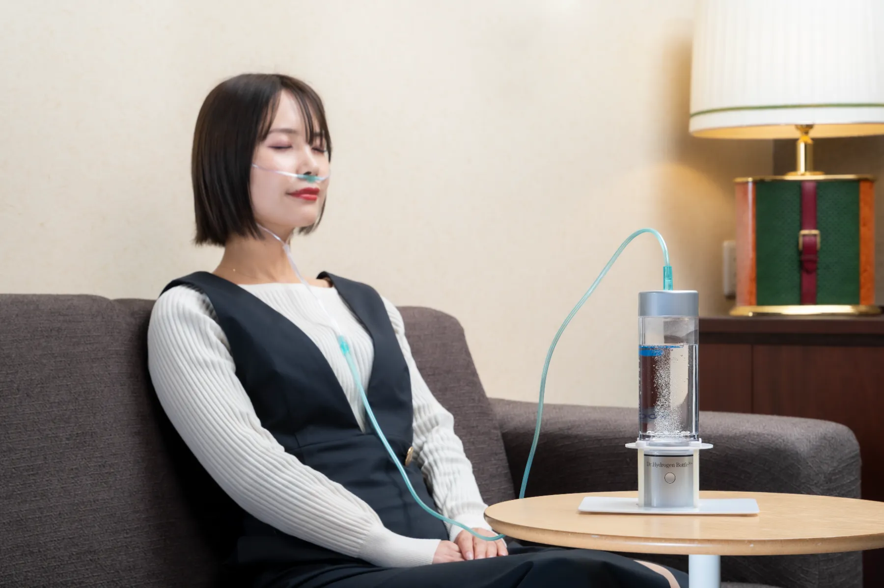 ソファでドクター水素ボトル＋の水素ガスを吸入する女性