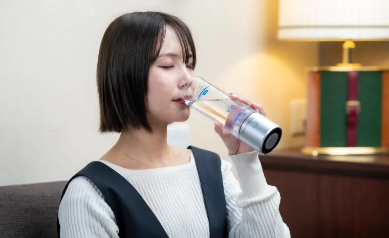 ボトルの水素水を飲む女性